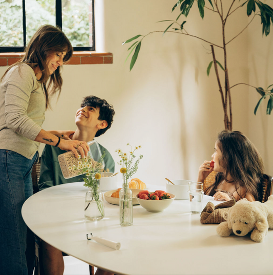 Mom pouring cereal for boy and girl sitting at kitchen table