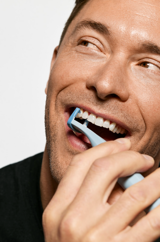 Man with brown hair smiling and flossing with blue Slate Origin flosser.